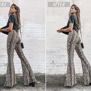 May include: A woman wearing a black t-shirt and brown and white snake print flared pants. She is standing in front of a white brick wall.
