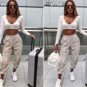 May include: A woman wearing a white crop top and beige pants with a repeating pattern of the words "Modern" and "Romantics". She is carrying a white backpack and a gray suitcase.