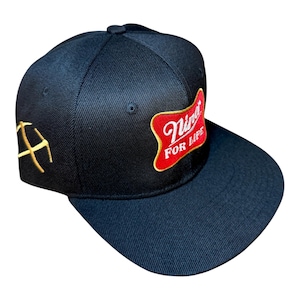 Peut inclure: Casquette de baseball noire avec une visière plate. Le chapeau présente un écusson rouge et doré avec le texte "Nina FOR LIFE". Un design de pioche doré est brodé sur le côté.