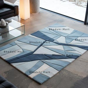 May include: A blue and white geometric patterned rug with the text "Bhadohi Mart" repeated throughout the design.