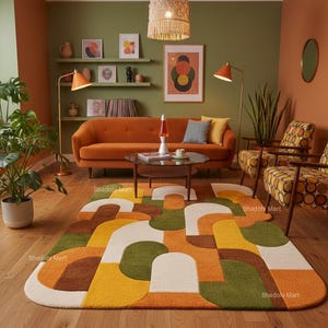 May include: A living room with a retro aesthetic. The room features an orange sofa, patterned rug, and two armchairs. The rug has a geometric design in shades of orange, yellow, brown, green, and white. Two orange lamps and a woven pendant light illuminate the space.