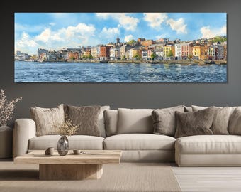 May include: Panoramic wall art print depicting a colorful cityscape along a waterfront. The buildings feature various colors, including yellow, red, and white, under a blue sky with fluffy clouds. The water reflects the sky and buildings.