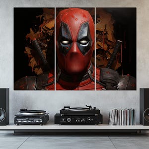 K&ouml;nnte beinhalten: Ein dreiteiliger Leinwanddruck mit Deadpool. Das Kunstwerk zeigt Deadpools rote und schwarze Maske und Kost&uuml;m vor einem dunklen Hintergrund mit Elementen einer Kampfszene. Der Druck befindet sich &uuml;ber einem wei&szlig;en Regal mit Stereoanlage.