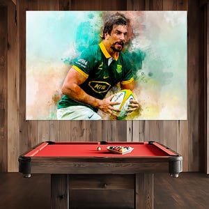 Puede incluir: Una pintura de acuarela de un jugador de rugby con una camiseta verde y dorada con el número "2004" en la manga. El jugador está sosteniendo una pelota de rugby y corriendo con la pelota. El fondo es un lavado de acuarela borroso de azul, verde y blanco.