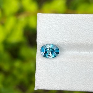 May include: A teal blue oval-shaped gemstone on a white background.