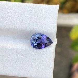 K&ouml;nnte beinhalten: Ein birnenf&ouml;rmiger, violetter Edelstein mit einem hellblauen Farbton.