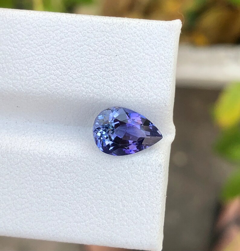 K&ouml;nnte beinhalten: Ein birnenf&ouml;rmiger, violetter Edelstein mit einem hellblauen Farbton.
