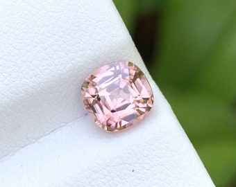May include: A light pink cushion-cut gemstone on a white background.