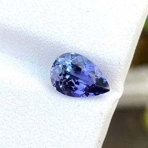 K&ouml;nnte beinhalten: Ein birnenf&ouml;rmiger, violetter Edelstein mit einem hellblauen Farbton. Der Edelstein ist auf einem wei&szlig;en Hintergrund platziert.