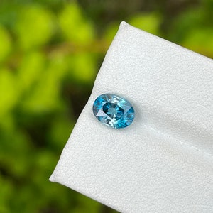 May include: Oval shaped blue gemstone with a light blue centre and a darker blue border.