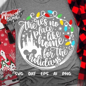 May include: A white graphic design on a gray t-shirt with the text "There's no place like home for the holidays" in a circle with a Mickey Mouse head and a silhouette of Cinderella's castle. The circle is decorated with a string of colorful Christmas lights.