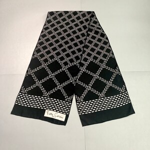 May include: Black and white patterned silk scarf with a white label that reads "Pierre Cardin Paris".