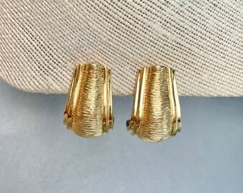 May include: A pair of gold-toned clip-on earrings with a textured, ribbed design.