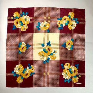 May include: A red and cream plaid silk scarf with a floral pattern. The flowers are yellow with teal green leaves. The scarf has a brown label with the text "Bell's Classics" on it.