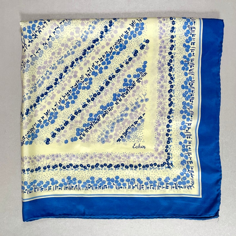 May include: A yellow silk scarf with a blue border and a floral pattern. The scarf has the word "Echos" printed in the center.