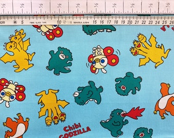 Puede incluir: Tela azul con un patrón repetido de personajes de Godzilla de dibujos animados. Los personajes son de varios colores, incluyendo verde, amarillo, rojo y blanco. La tela tiene el texto "Chibi Godzilla" impreso en ella.