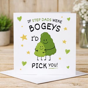 May include: A white greeting card featuring a cartoon illustration of two green bogeys hugging. The text reads IF STEP DADS WERE BOGEYS I'D PICK YOU! The design includes small yellow stars and green hearts scattered across the front of the card.