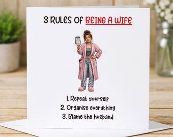 May include: A square greeting card with the text 3 RULES OF BEING A WIFE in black and red. Below is an illustration of a person in a pink robe, gray polka dot pants, and pink slippers holding a phone. The text reads 1. Repeat yourself 2. Organise everything 3. Blame the husband.