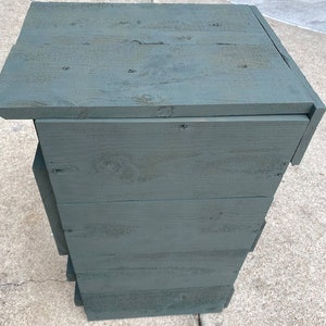 May include: A dark green wooden storage unit with four shelves. The unit is made from reclaimed wood and has a rustic look.