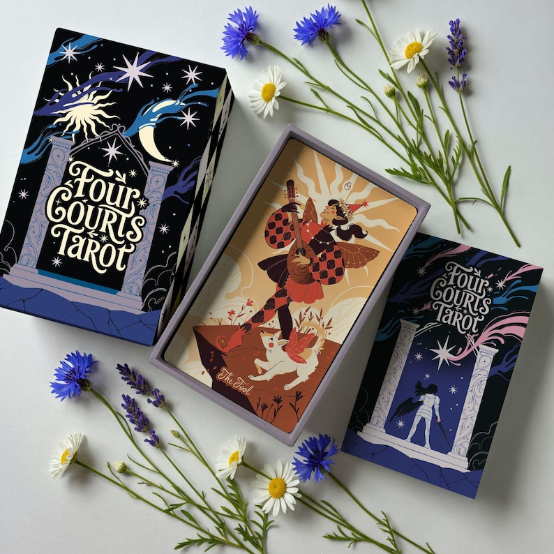Op de afbeelding: Een tarotkaartspel met een doos en kaarten met illustraties. De doos is zwart met een nachthemelontwerp en de tekst "Four Courts Tarot". De kaarten tonen figuren en sc&egrave;nes. Bloemen zijn rond het deck gerangschikt.