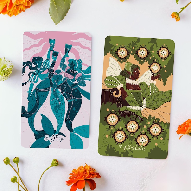 Op de afbeelding: Twee tarotkaarten met illustraties. E&eacute;n kaart toont drie zeemeerminnen die bekers vasthouden, met de tekst "3 of Cups". De andere kaart toont een vrouw in een groene jurk met de tekst "9 of Pentacles".