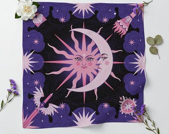 Op de afbeelding: Een vierkante stoffen doek met een centrale illustratie van een roze zon met een menselijk gezicht die een bleke maansikkel overlapt. De achtergrond is dieppaars met wervelende lijnen, roze sterren, een gevleugeld zwaard en een decoratieve lantaarn.