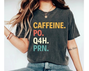 May include: A dark gray t-shirt with the text "CAFFEINE. PO. Q4H. PRN." printed in colorful letters.