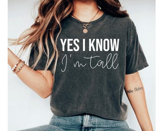 May include: A dark gray t-shirt with the text "YES I KNOW I'm tall" in white lettering.