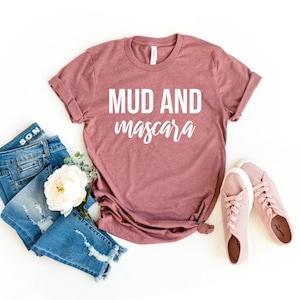 May include: A mauve t-shirt with the text "MUD AND mascara" in white lettering.