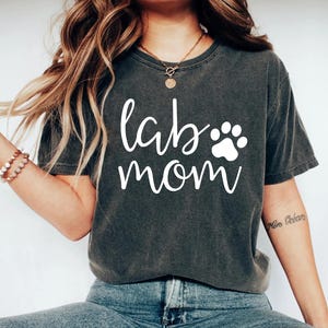 May include: A dark gray t-shirt with the text "lab mom" in white lettering and a white paw print.