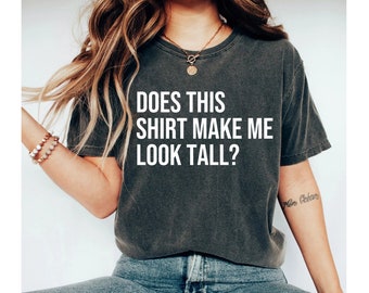 May include: A dark gray t-shirt with the text "Does this shirt make me look tall?" printed in white.