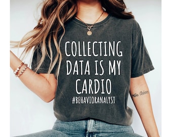 May include: A dark gray t-shirt with white text that reads "Collecting data is my cardio #behavioranalyst".