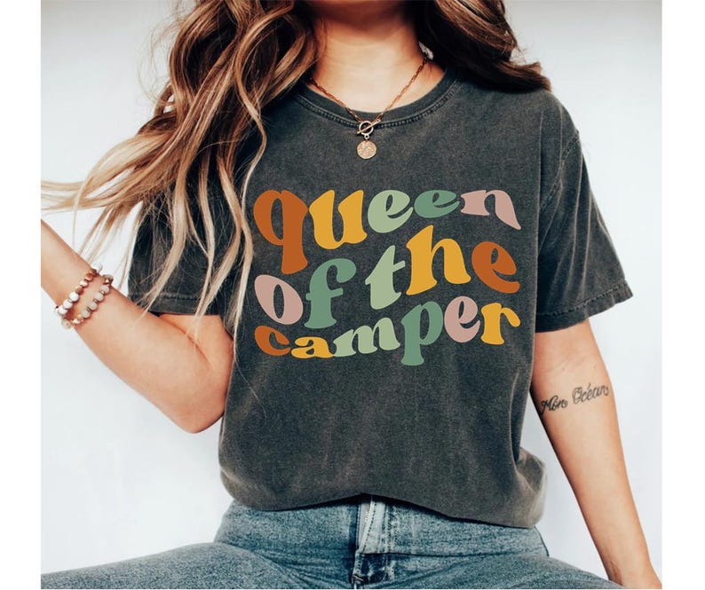 May include: A dark gray t-shirt with the text "Queen of the Camper" in colorful retro lettering.
