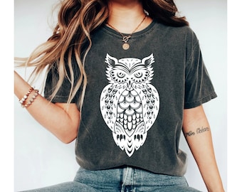 May include: A dark gray t-shirt with a white owl graphic. The owl is detailed with intricate patterns and has a large, round head.