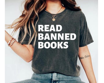May include: A dark gray t-shirt with the text "READ BANNED BOOKS" printed in white on the front.