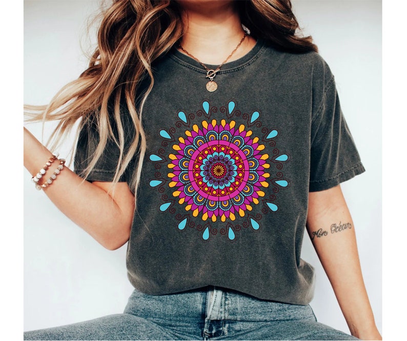 May include: A dark gray t-shirt with a colorful mandala design printed on the front. The mandala features a variety of colors, including pink, blue, yellow, and orange.