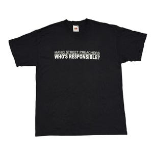 May include: Black t-shirt with the text "MANIC STREET PREACHERS WHO'S RESPONSIBLE?" in white. The shirt has short sleeves and a crew neck. The Fruit of the Loom logo is visible on the upper part of the shirt.