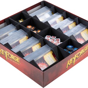 Może przedstawiać: Czarna wkładka organizatora do gry planszowej KeyForge: Call of the Archons. Wkładka ma przegrody na karty, kości i żetony. Wkładka znajduje się w czerwonym pudełku z logo gry.