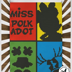 May include: A colorful crochet blanket with a red, yellow, green, and blue background. The blanket features a black silhouette of a hand, a deer, a hat, and a flower. The text "miss polk adot" is written in black on the red square.