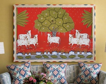 Puede incluir: Un salón con un sofá, cojines estampados y una mesa de centro. Encima del sofá, una obra de arte enmarcada con fondo rojo y un árbol con vacas. Dos lámparas flanquean el sofá.