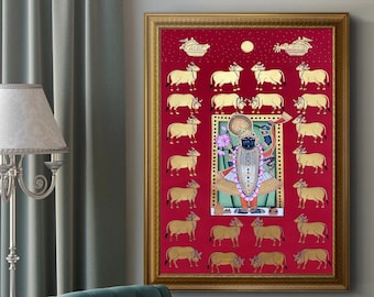 Puede incluir: Una obra de arte enmarcada con un marco dorado, que representa una figura central azul rodeada de vacas doradas sobre un fondo rojo. La obra de arte es probablemente de importancia cultural o religiosa.