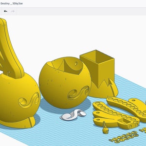 Op de afbeelding: Een 3D-geprint model van een geel ei met een ontwerp aan de zijkant, gebroken in meerdere stukken. De stukken omvatten een bovenkant, een onderkant en een apart stuk met een ontwerp aan de zijkant. Er zijn ook verschillende kleinere stukken, waaronder een kleine schedel en een slang.