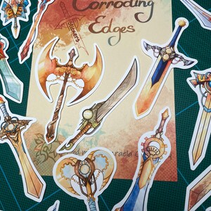 May include: A set of 10 colorful stickers featuring various fantasy weapons with intricate details. The stickers are designed with a steampunk aesthetic and feature gears, chains, and other mechanical elements. The stickers are labeled "Corroding Edges Stickers".