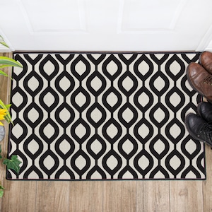 May include: Black and white geometric doormat with a repeating pattern of interlocking ovals. The doormat has a black border and is made of a soft, durable material.