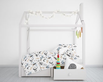 May include: A white canopy bed with a white and blue space-themed bedding set. The bedding features rockets, stars, planets, and UFOs. A wooden toy rocket is on the bed next to a white pillow with a black star pattern.