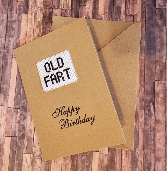 A birthday card where the design IS a tiny hand-stitched cross stitch — the medium is the joke, and it's genuinely clever.