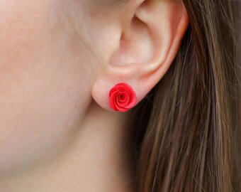 May include: A pair of red rose flower stud earrings. The earrings are small and delicate, and they would make a great gift for a special occasion.