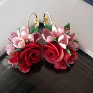 Peut inclure: Une paire de boucles d'oreilles compos&eacute;es de grappes de fleurs sculpt&eacute;es dans des tons rouge profond, rose clair et mauve, agr&eacute;ment&eacute;es de petites feuilles vertes. Les compositions florales sont fix&eacute;es sur des anneaux dor&eacute;s avec fermoir.