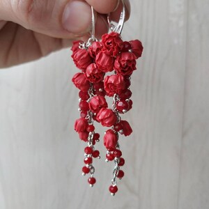 May include: Red flower dangle earrings with silver hooks and red crystal beads.