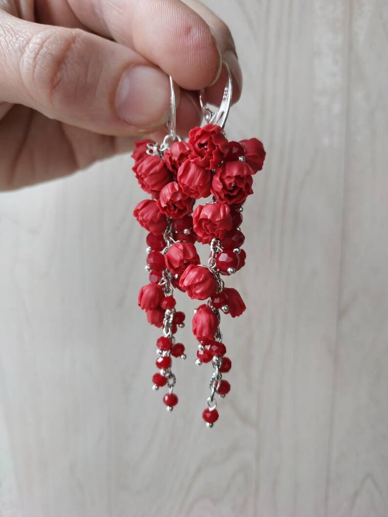 May include: Red flower dangle earrings with silver hooks and red crystal beads.